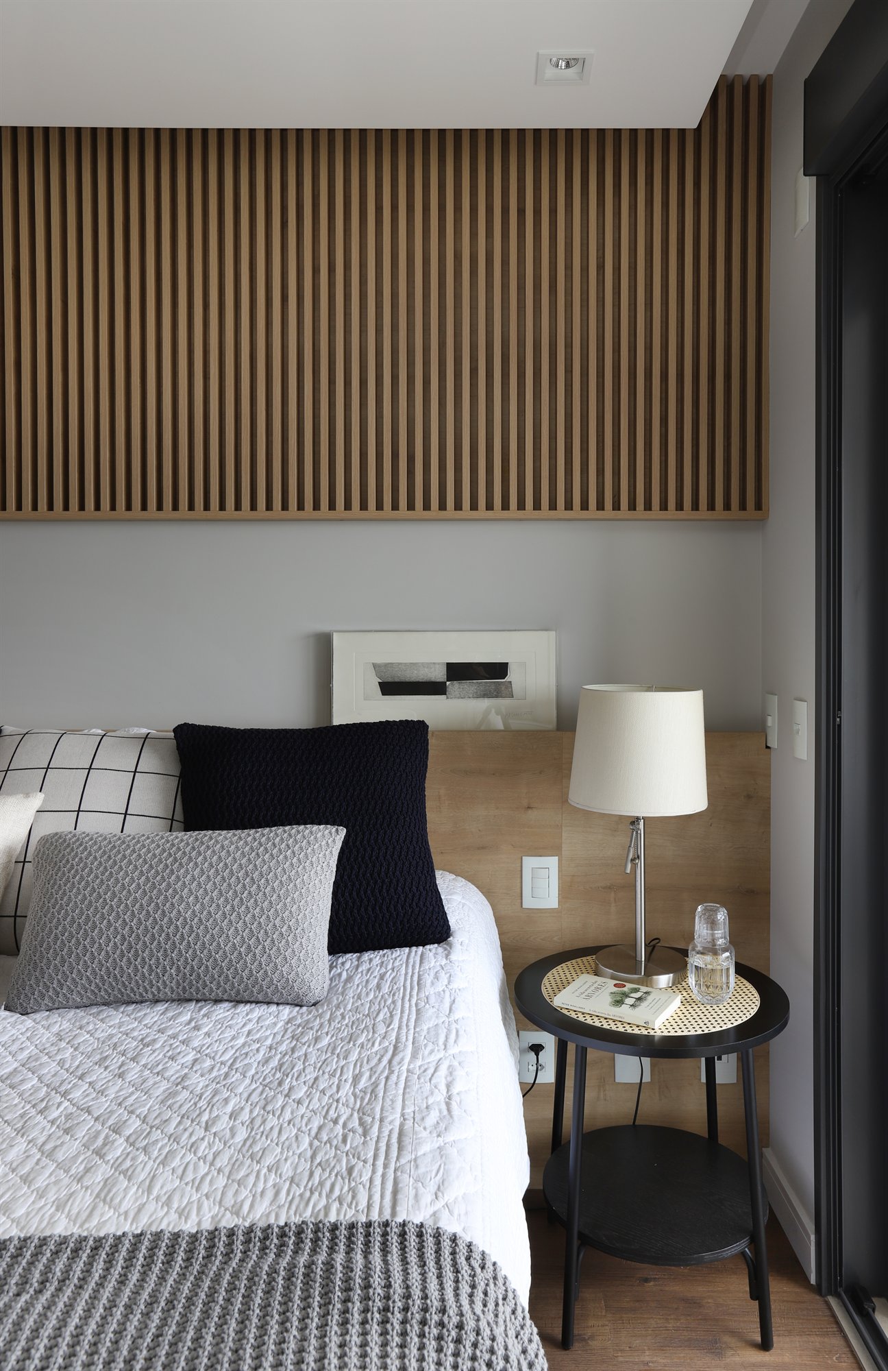 Projeto Lapa: Detalhe da cama com mesa lateral, luminária e painel ripado.