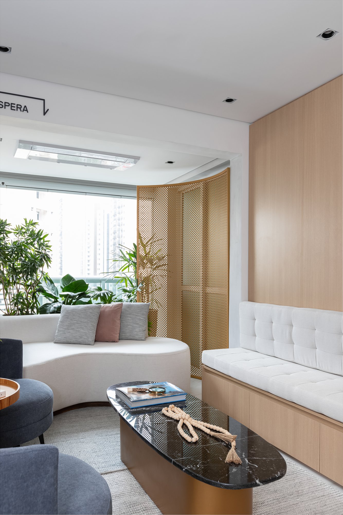 Projeto Moema: Sala de espera com sofá curvo, divisória vazada e mesa de centro.