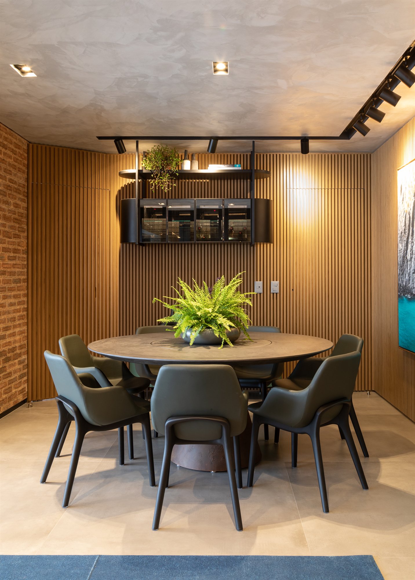 Projeto Mooca: Sala de jantar com mesa redonda, cadeiras e parede de ripas de madeira.