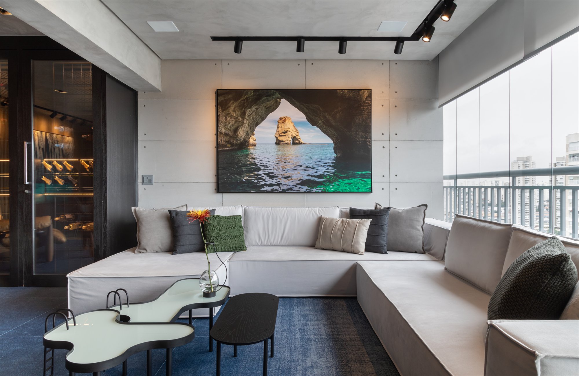 Projeto Mooca: Sala com sofá branco em L, arte na parede e vista para a varanda.