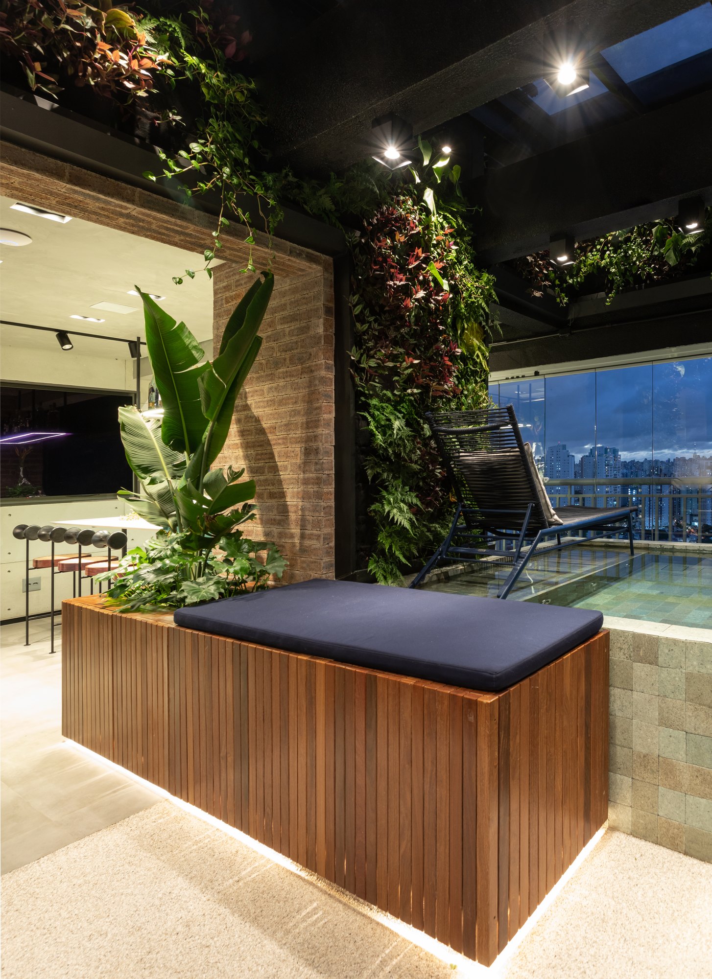 Projeto Mooca: Varanda com jardim vertical, banco ripado e piscina com vista para a cidade.