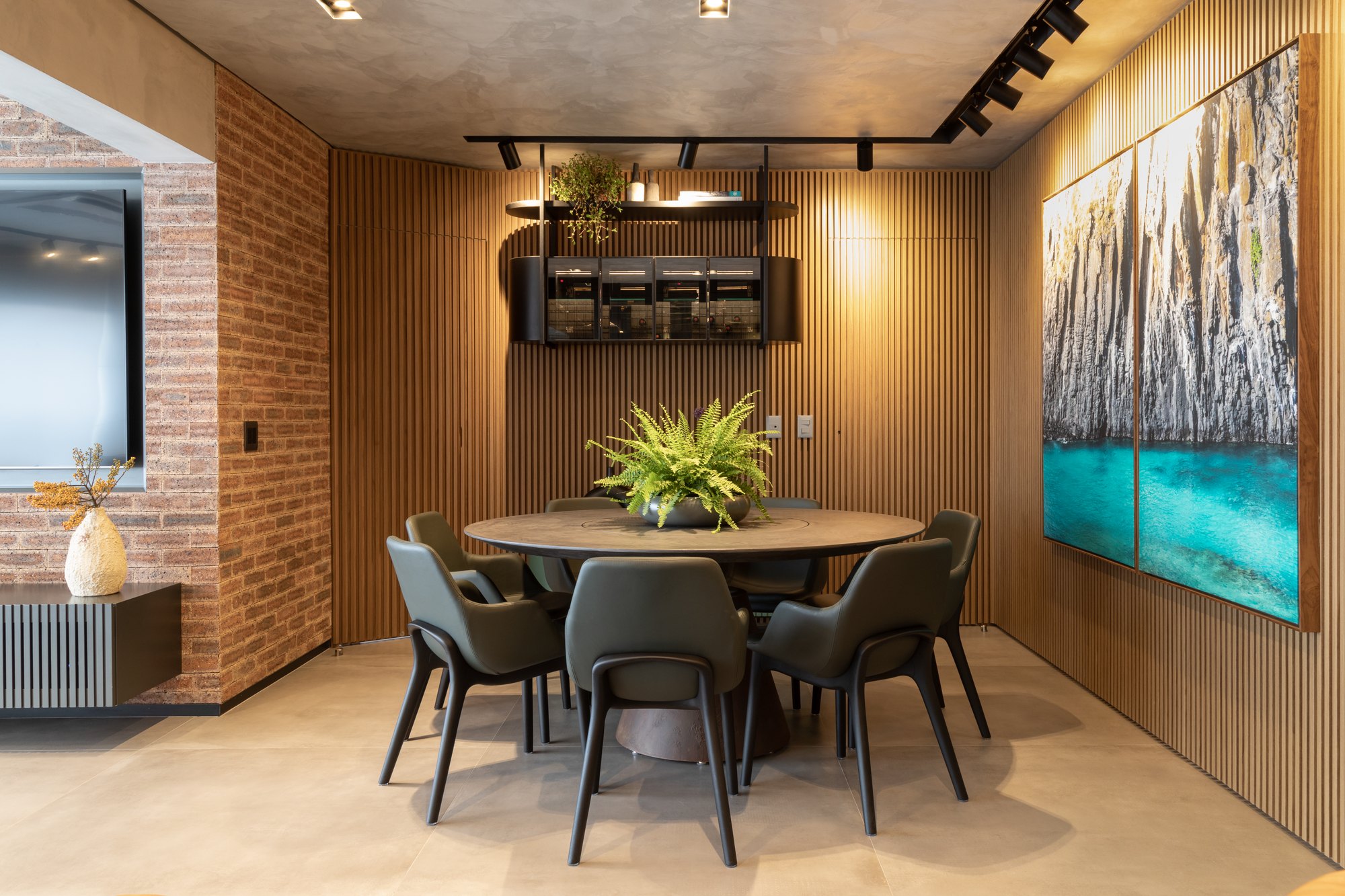 Projeto Mooca: Sala de jantar com mesa redonda, cadeiras e parede ripada de madeira.
