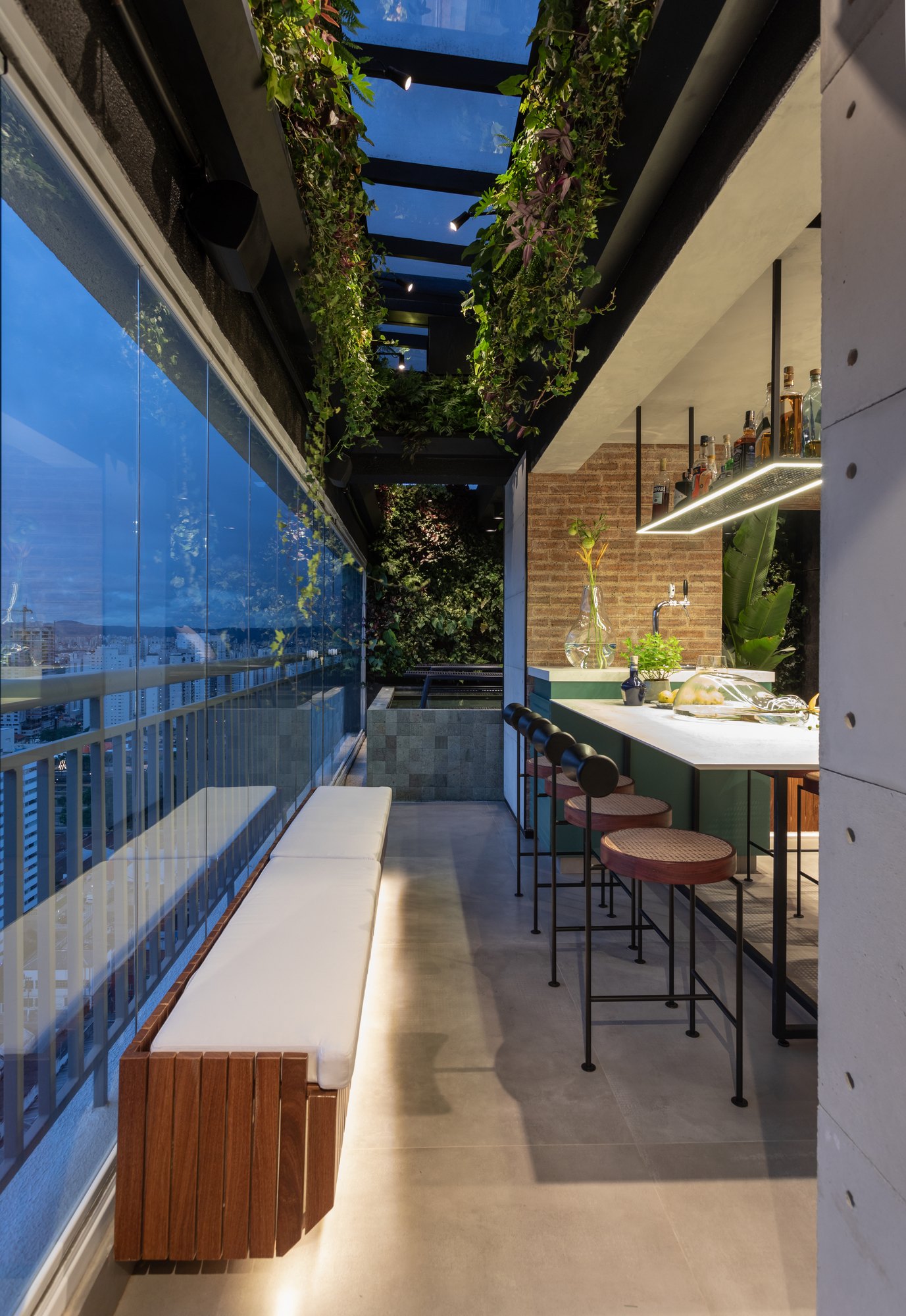 Projeto Mooca: Passagem da varanda com banco de madeira, jardim vertical e iluminação embutida.