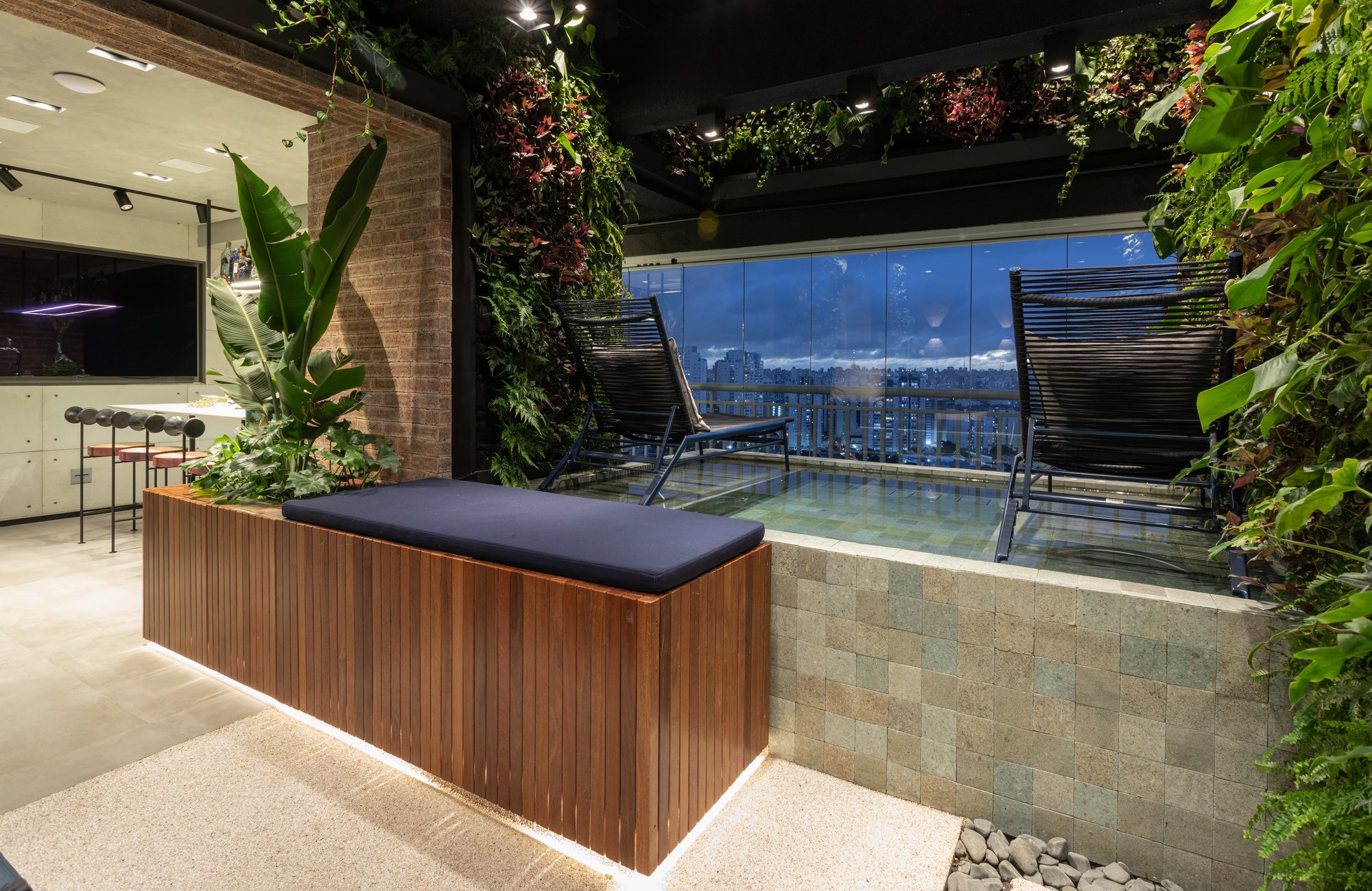 Projeto Mooca: Deck com banco ripado de madeira, piscina e área gourmet integrada.