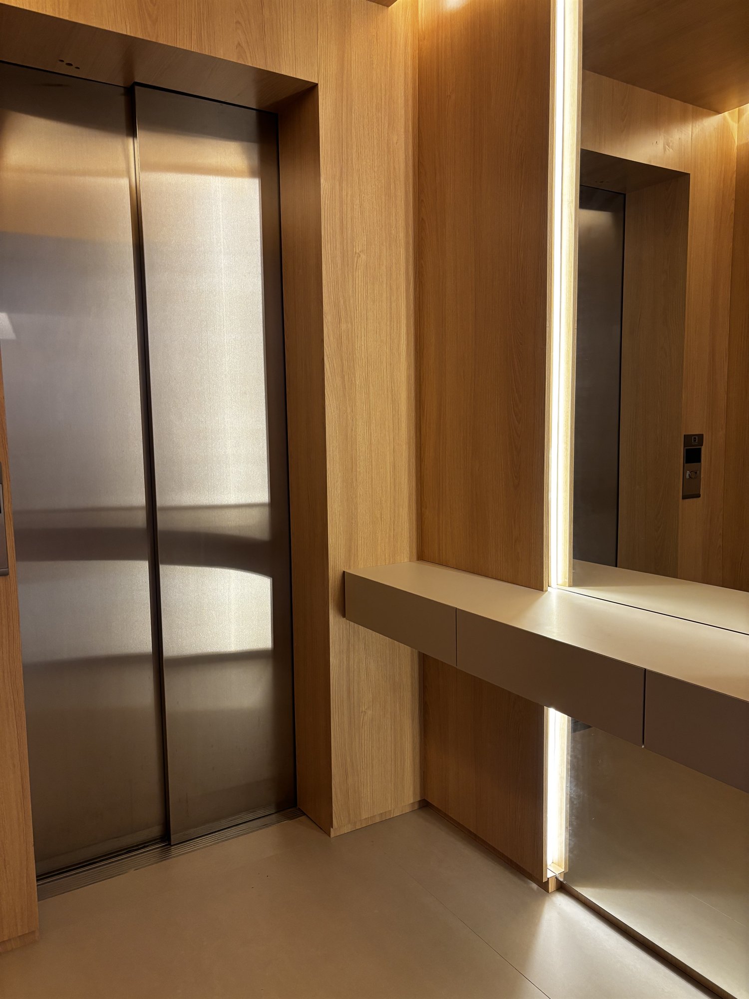 Projeto Perdizes: Hall com painel amadeirado, espelho e console flutuante.