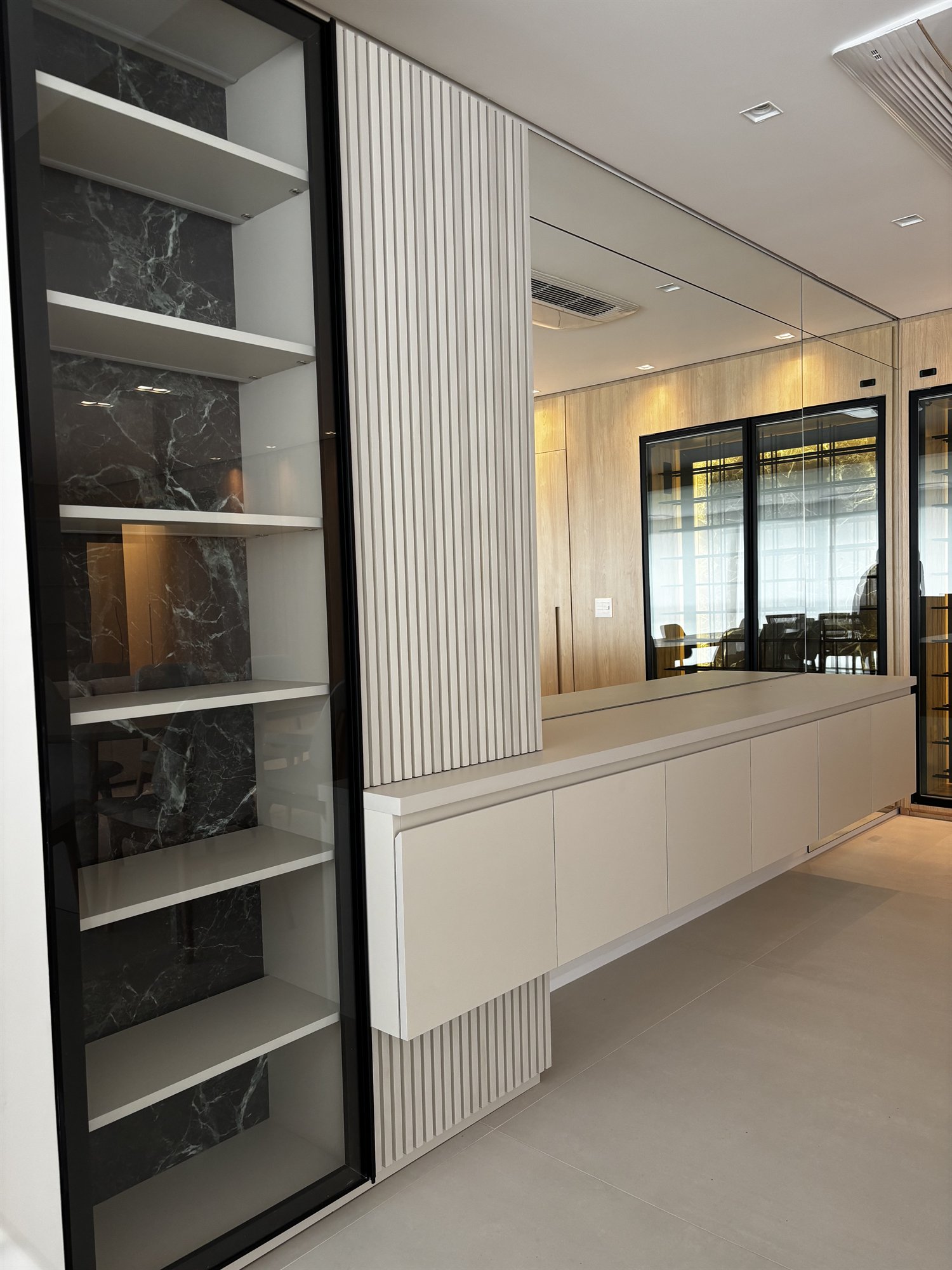 Projeto Perdizes: Rack branco, painel ripado iluminado e estante lateral escura.