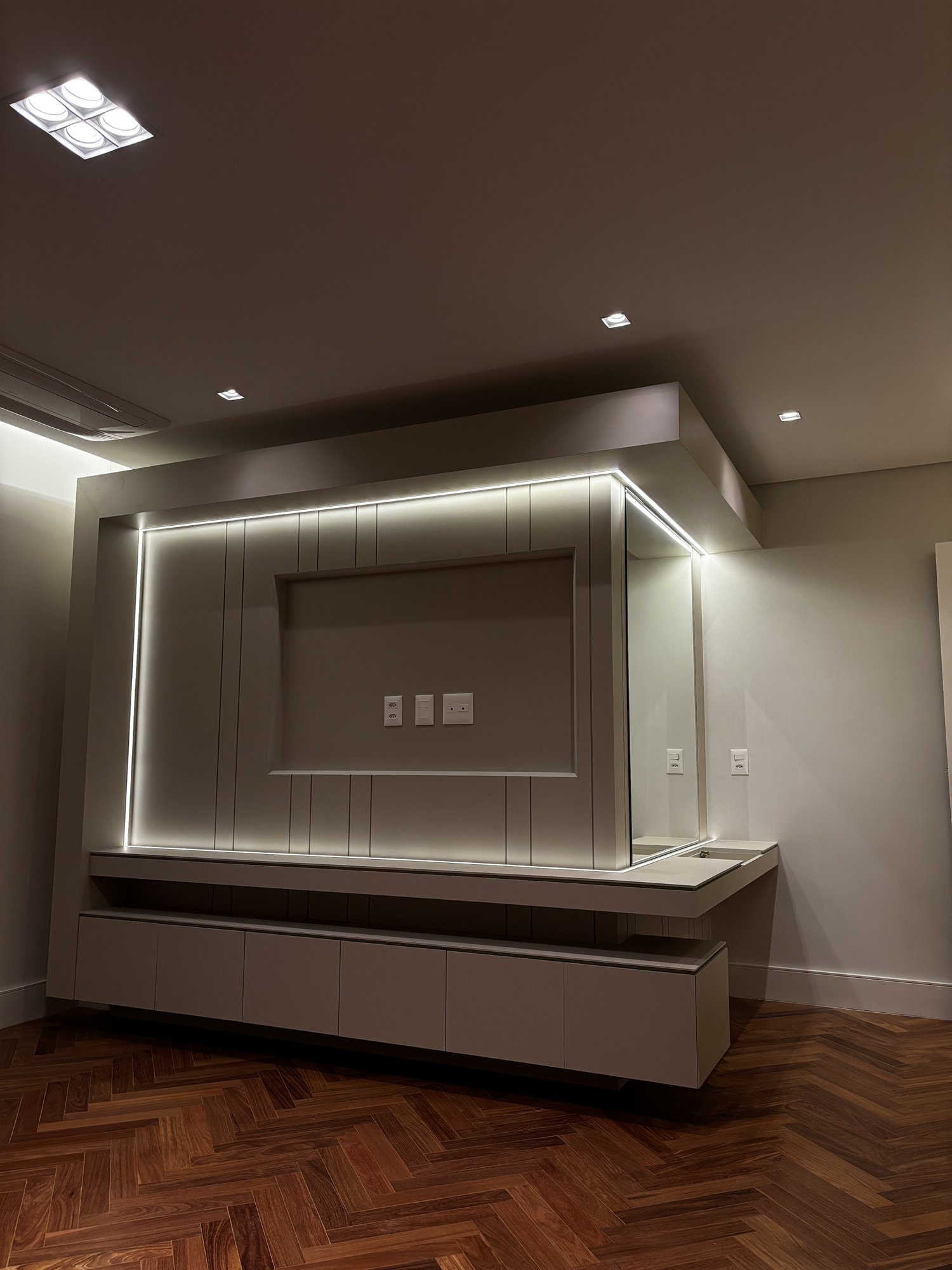 Projeto Perdizes: Sala com painel de TV e bancada flutuante iluminados.