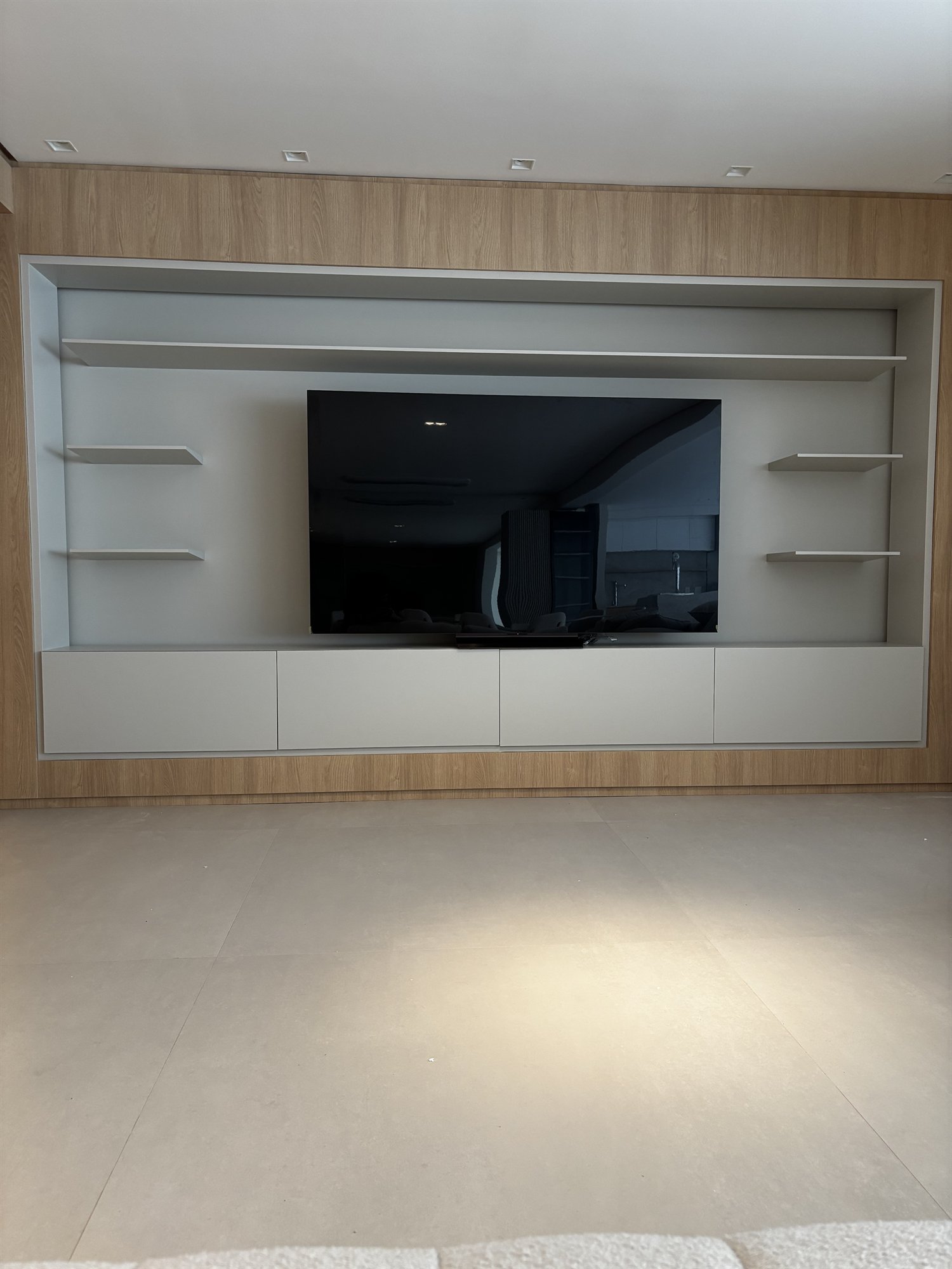 Projeto Perdizes: Painel de TV com armário inferior branco e prateleiras laterais.