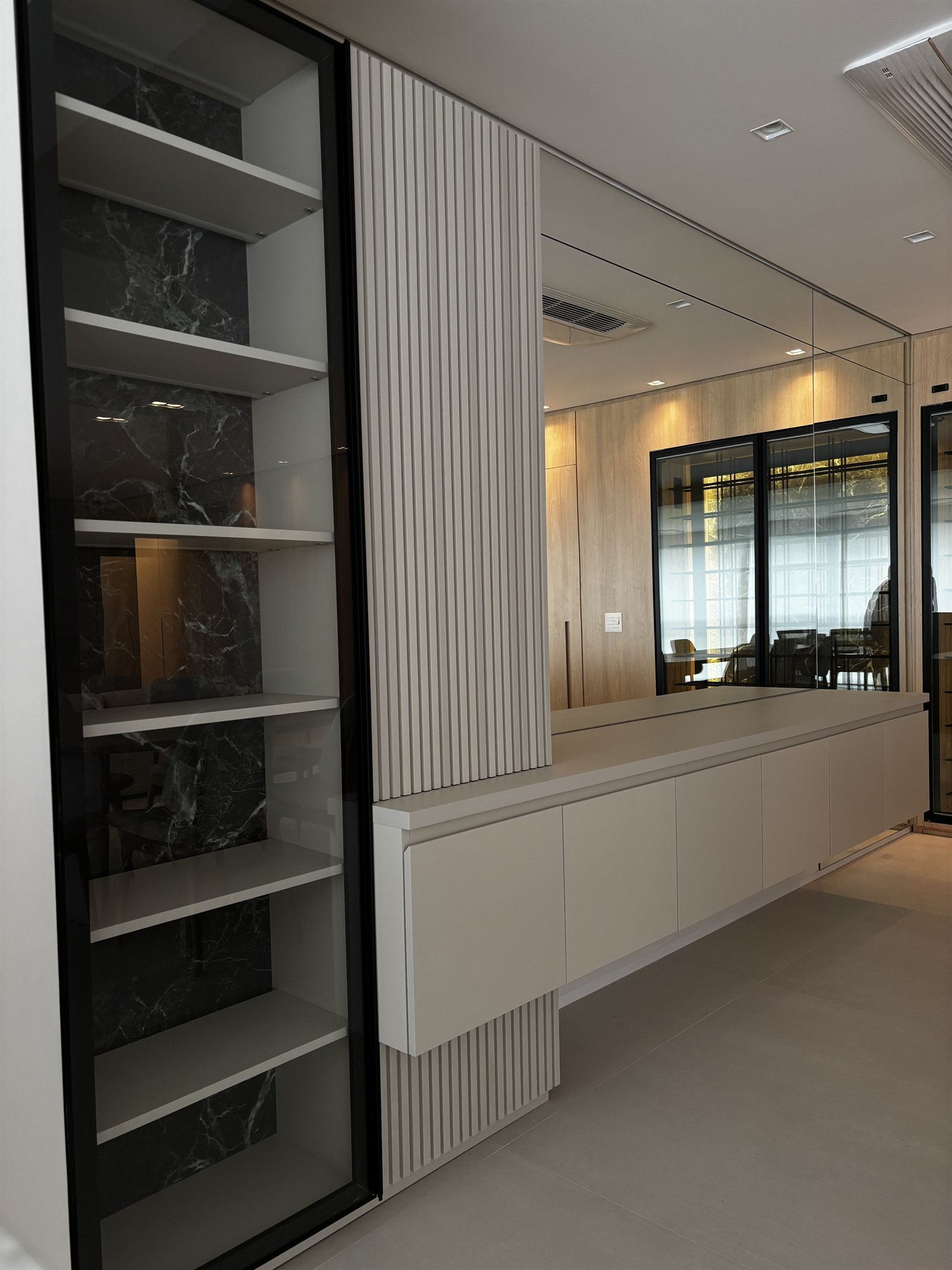 Projeto Perdizes: Vista ampla da marcenaria da sala com painel ripado, estante e rack branco.
