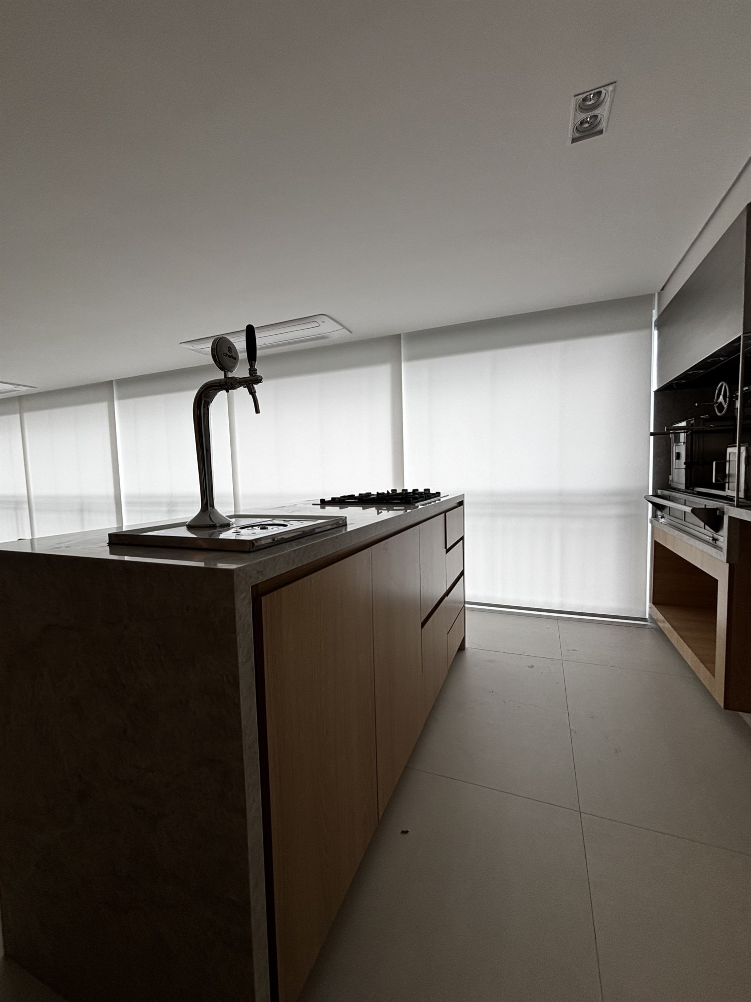 Projeto Perdizes: Cozinha com bancada, armários de madeira, cooktop e janela ampla.