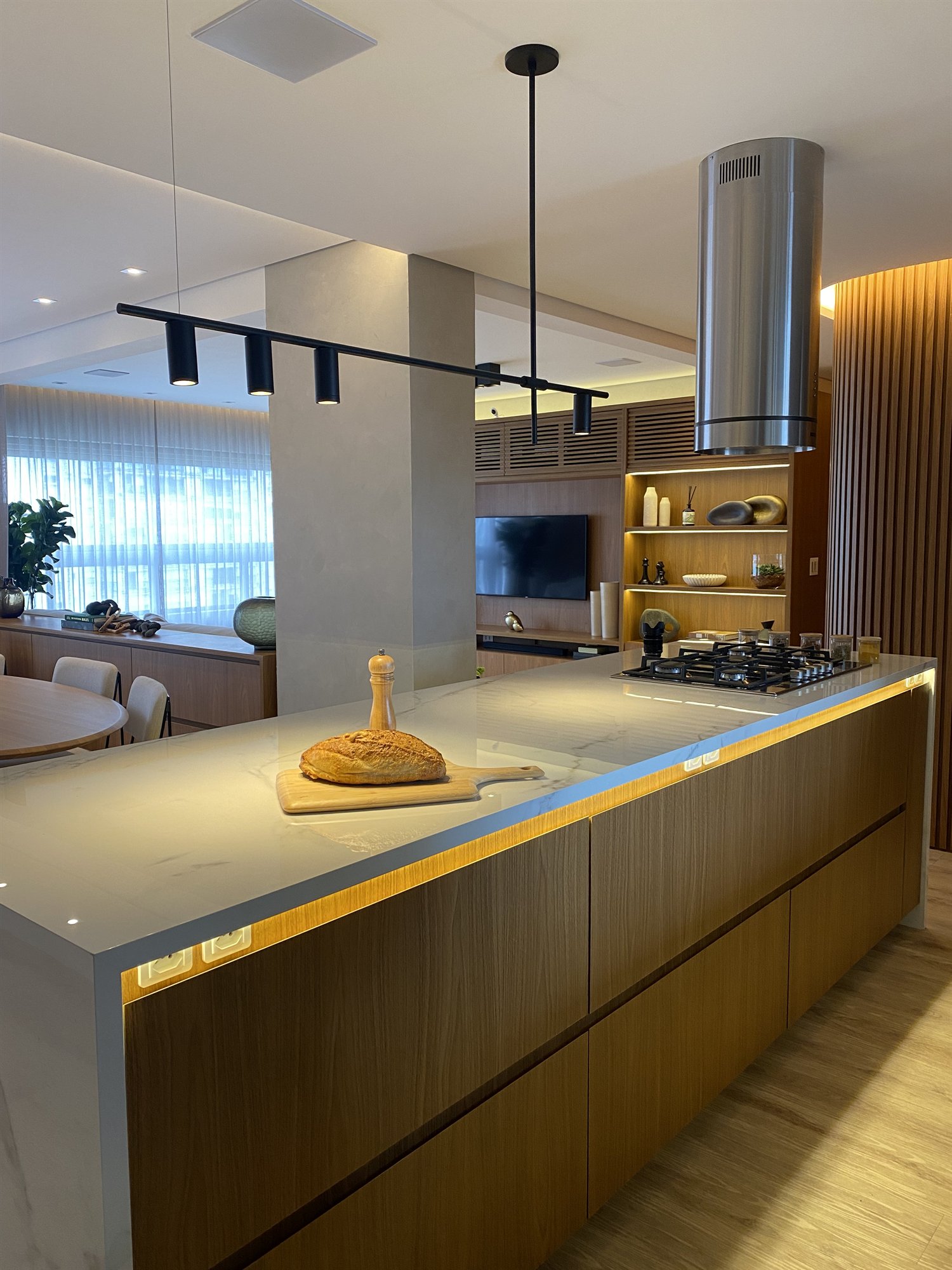 Projeto Itaim Bibi 2024: Cozinha planejada com ilha de madeira, cooktop e coifa.