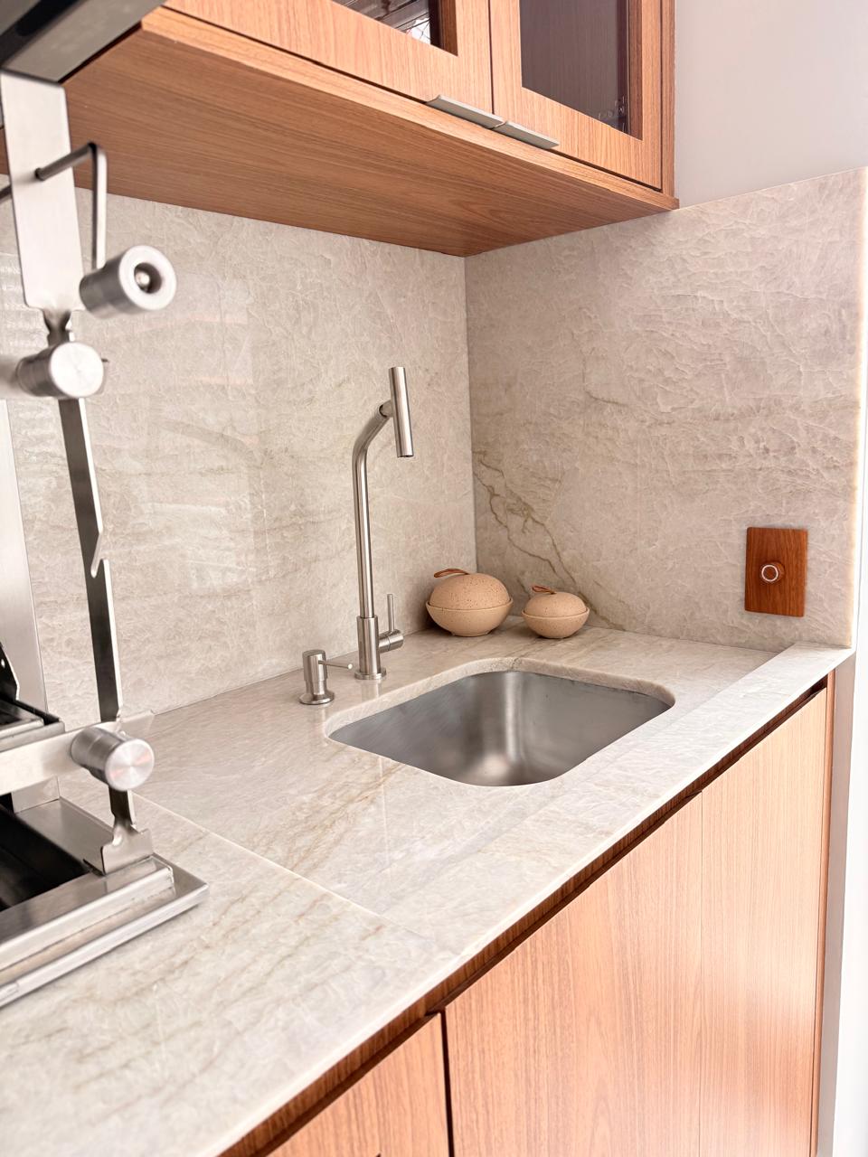 Projeto Santo Amaro: Bancada de cozinha em pedra clara com cuba e marcenaria de madeira.