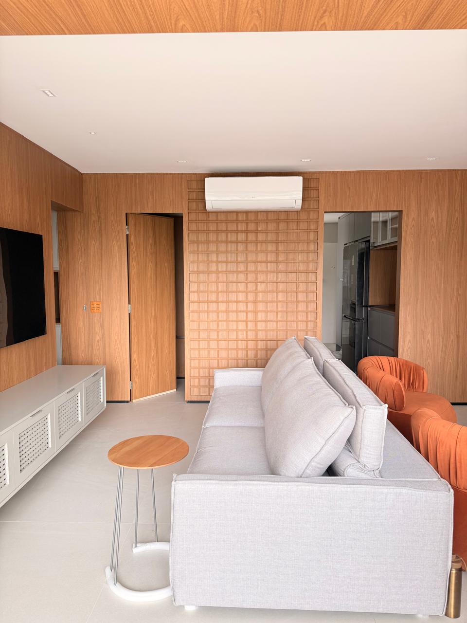 Projeto Santo Amaro: Sala com painel ripado, sofá e poltronas.