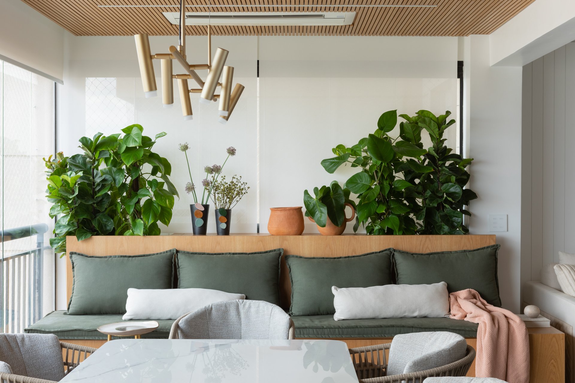 Projeto Vila Olimpia: Detalhe do banco verde com plantas e painel de madeira.
