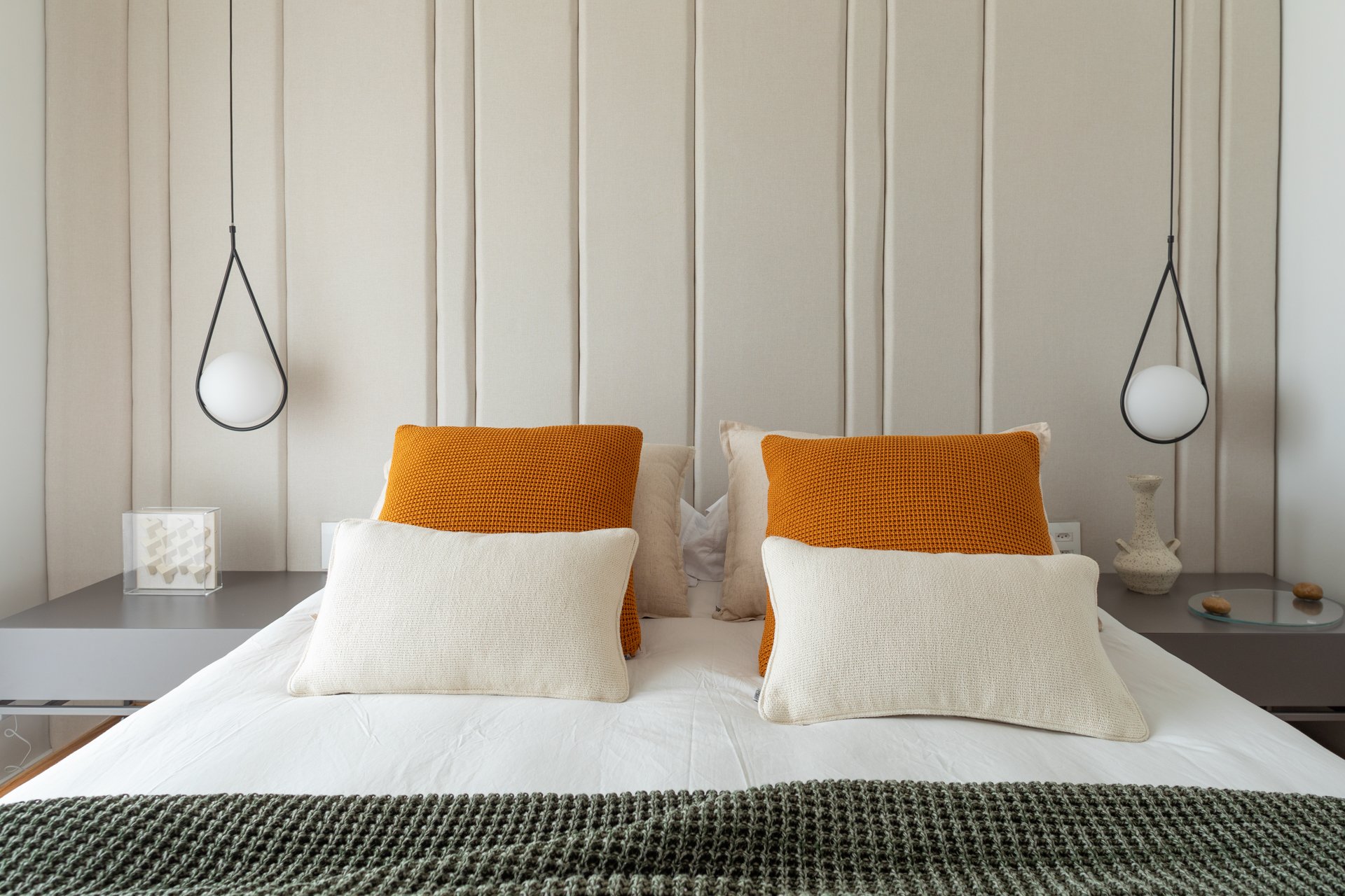Projeto Vila Olimpia: Quarto com cama de casal, cabeceira estofada e almofadas terracota.
